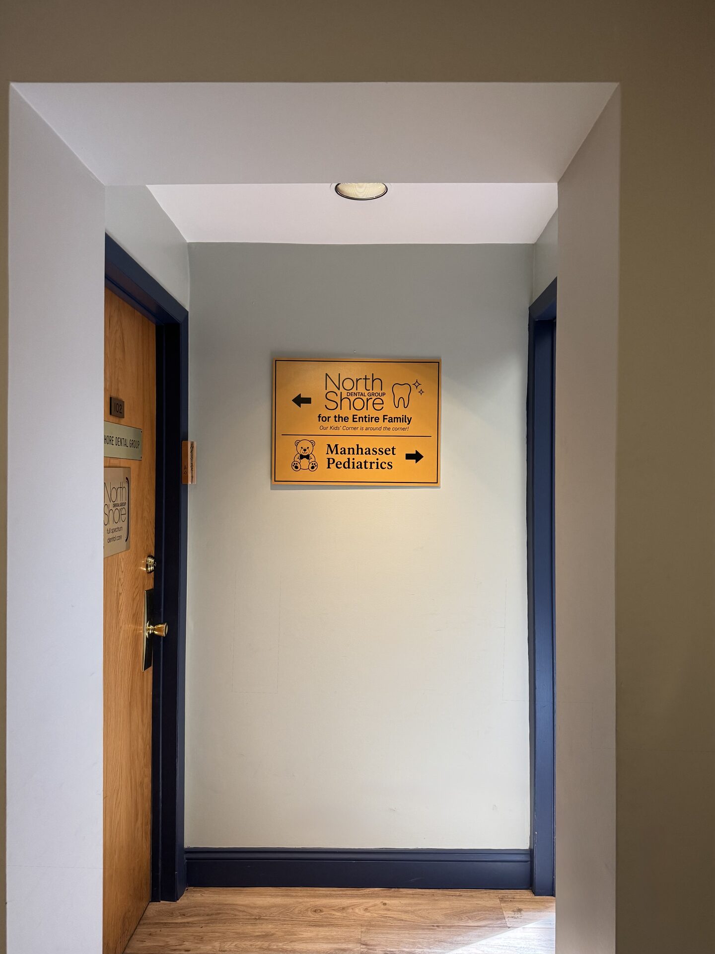 Suite 102 entrance door to North Shore Dental Group beside the directional sign for the practice and Manhasset Pediatrics